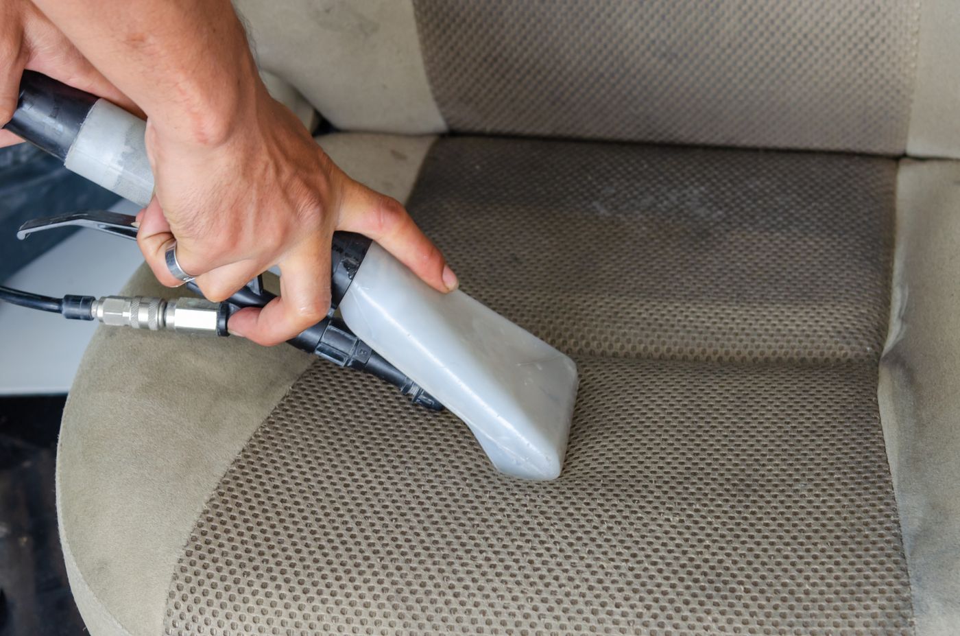 Innenreinigung: Autositz wird mit einem Reinigungsgerät behandelt